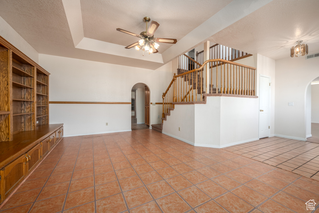 Unfurnished living room featuring a textured ceiling, tile patterned flooring, and ceiling fan