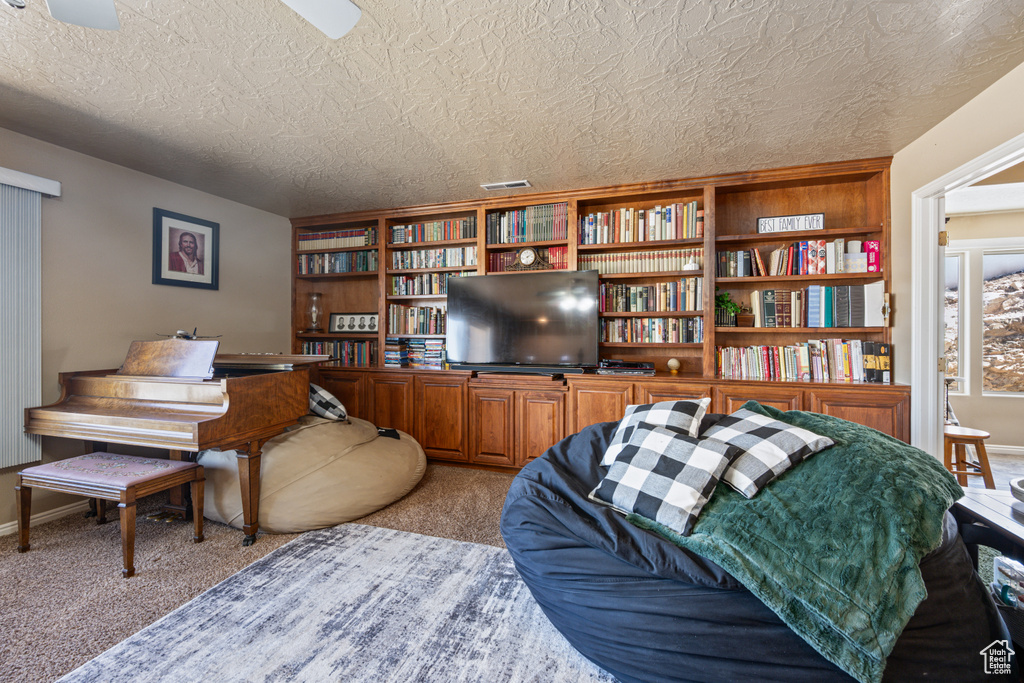 Carpeted living room with a textured ceiling and ceiling fan