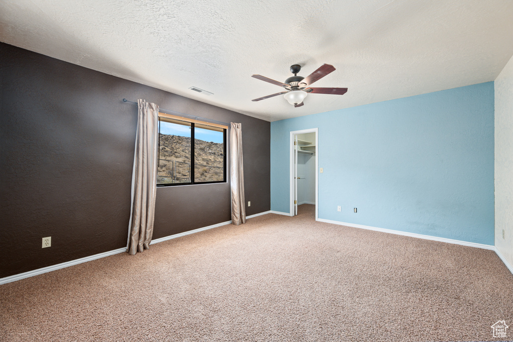 Carpeted spare room with ceiling fan and a textured ceiling