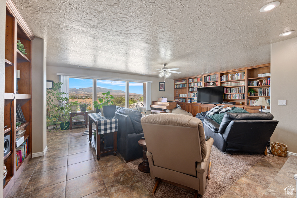 Tiled living room with ceiling fan and a textured ceiling