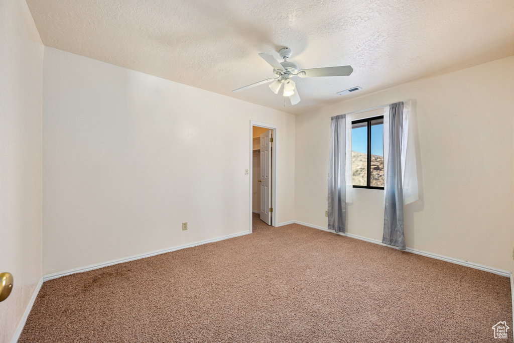 Carpeted empty room with a textured ceiling and ceiling fan