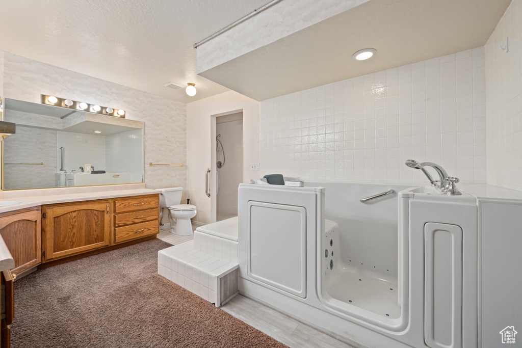 Bathroom featuring vanity, a bathing tub, toilet, and a textured ceiling