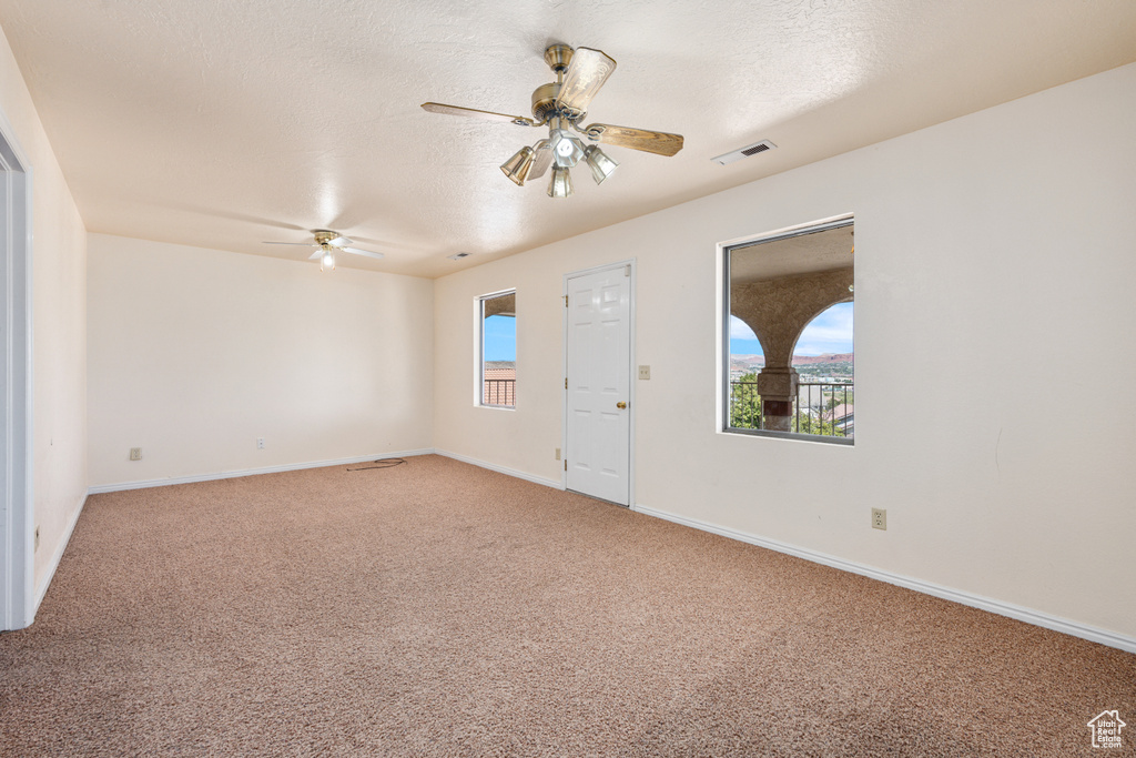 Carpeted spare room with a textured ceiling and ceiling fan