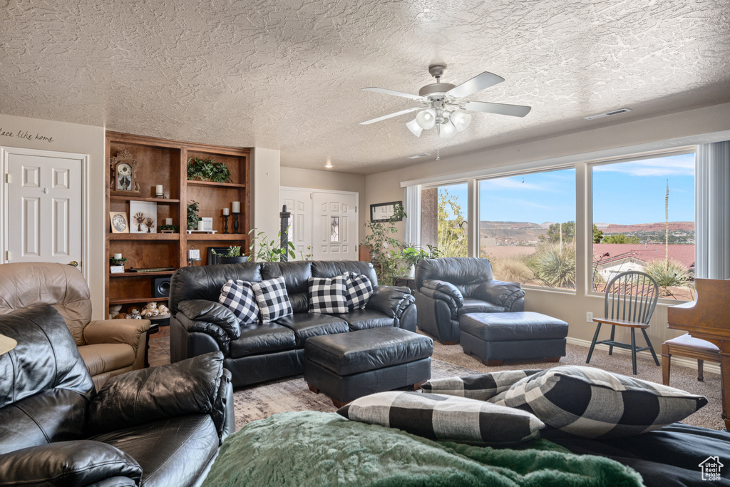 Carpeted living room featuring a textured ceiling and ceiling fan