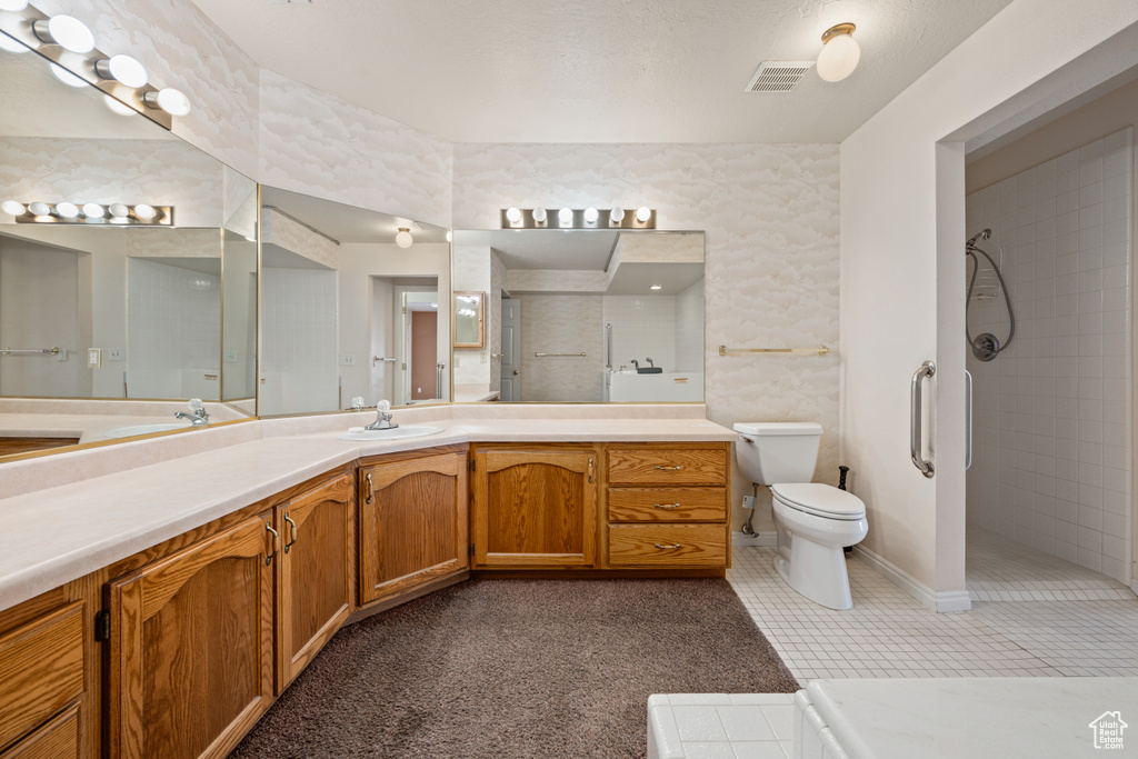 Bathroom with a tile shower, vanity, tile patterned flooring, and toilet