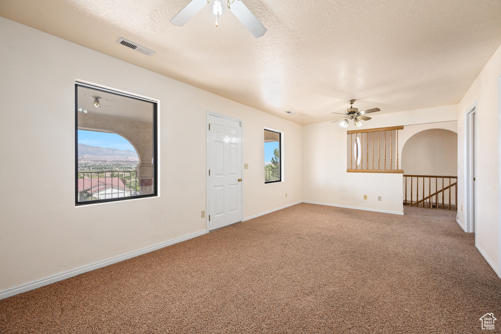 Foyer entrance featuring a textured ceiling, carpet, and ceiling fan