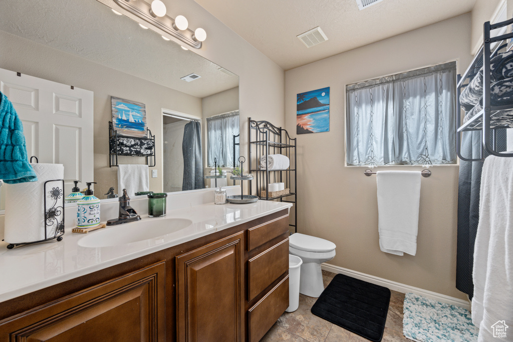 Bathroom featuring a healthy amount of sunlight, vanity, and toilet