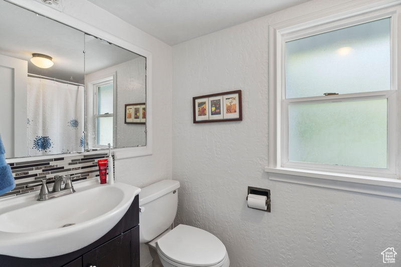 Bathroom with vanity, toilet, and decorative backsplash