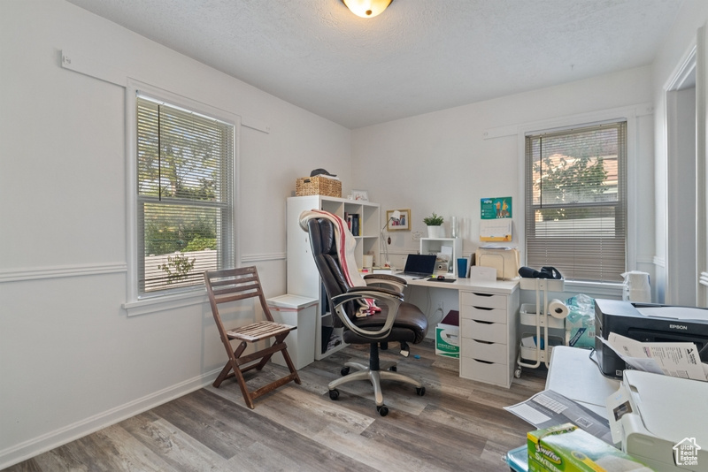 Office space featuring light wood-type flooring and a textured ceiling