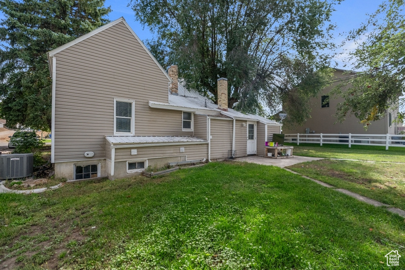 Rear view of property featuring a patio, a lawn, and central AC unit