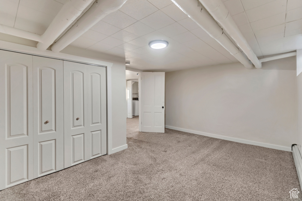 Basement featuring light carpet and a baseboard radiator