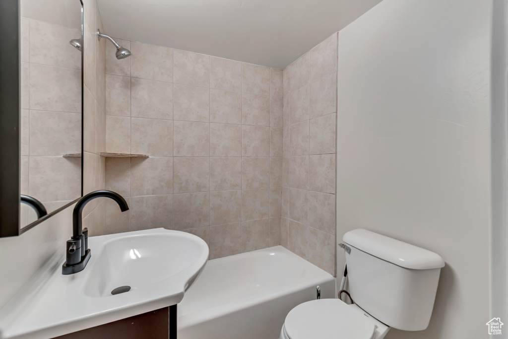 Full bathroom featuring tiled shower / bath combo, vanity, and toilet