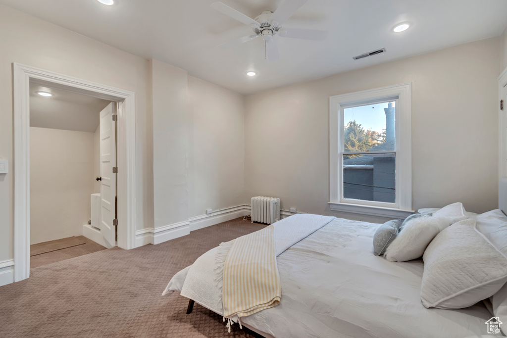 Carpeted bedroom featuring radiator heating unit and ceiling fan