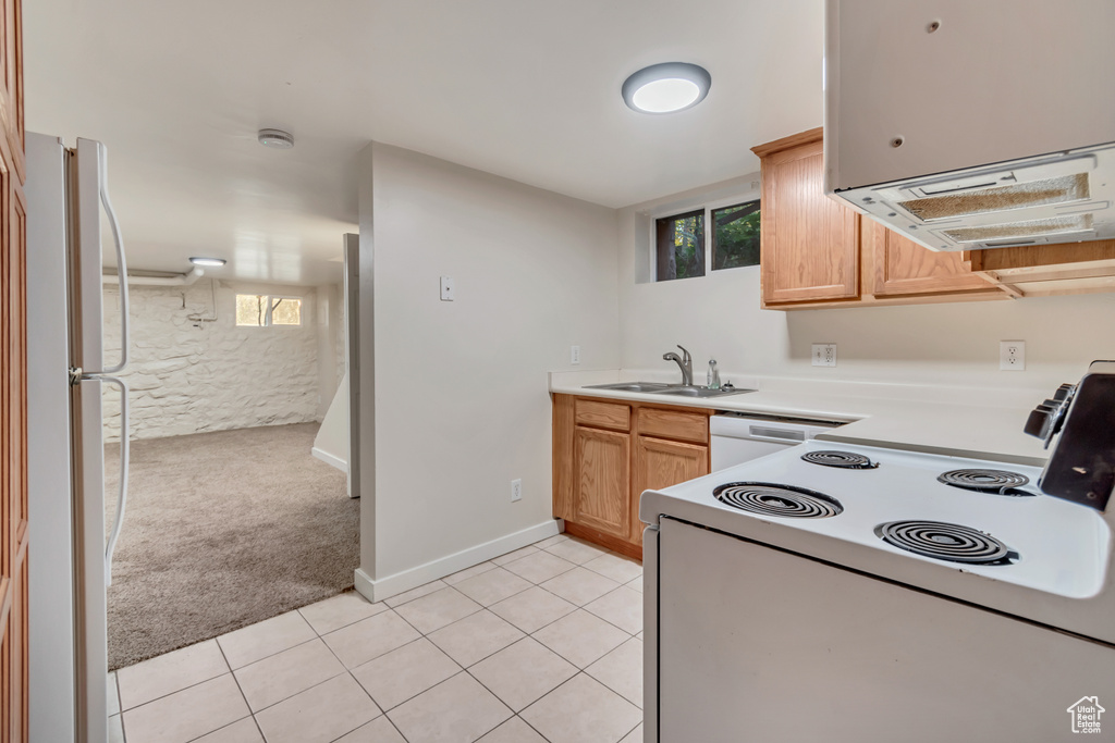 Kitchen with white appliances, light tile patterned flooring, and sink