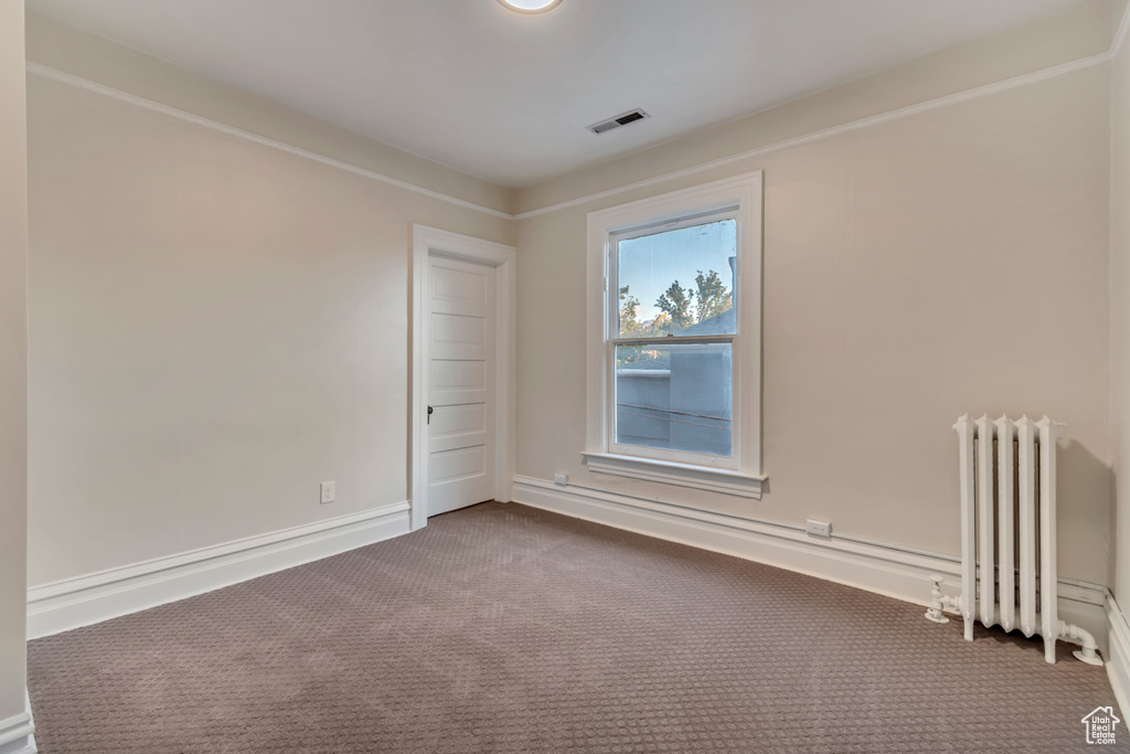 Spare room with radiator, carpet flooring, and crown molding