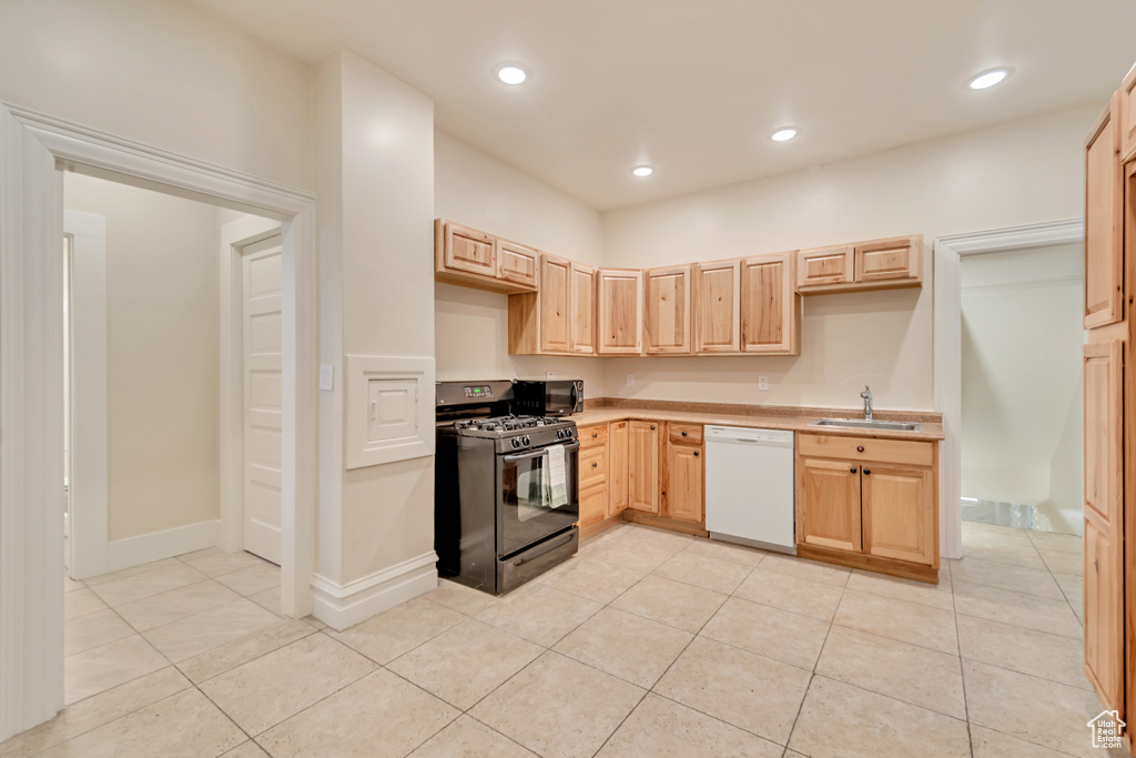 Kitchen featuring white dishwasher, light tile patterned flooring, light brown cabinetry, and black range with gas cooktop