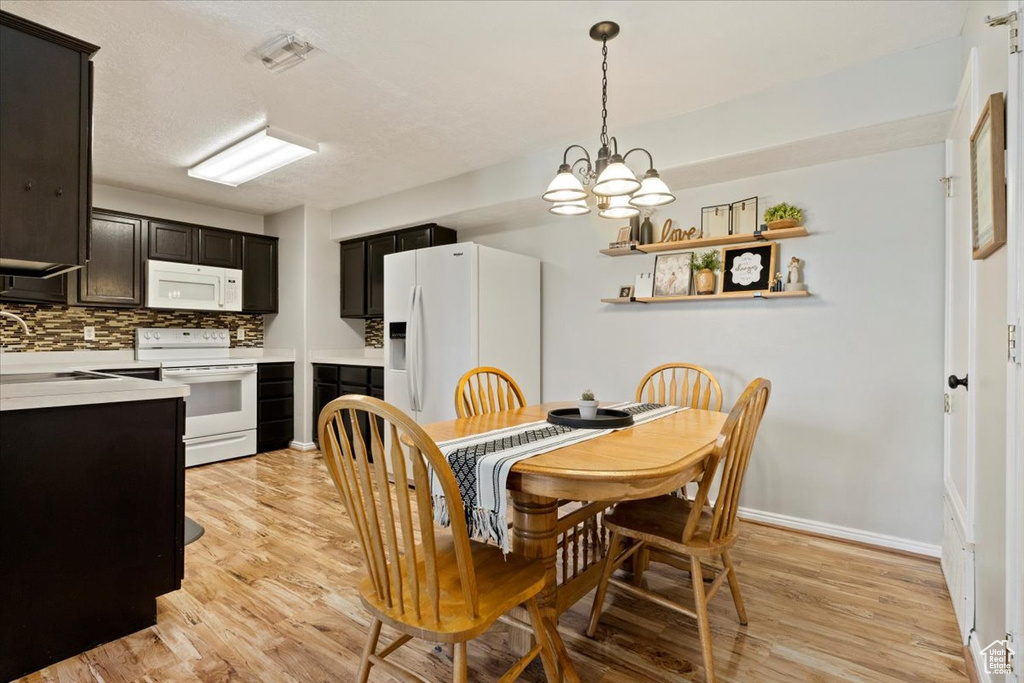 Dining room with an inviting chandelier, light hardwood / wood-style flooring, sink, and a textured ceiling