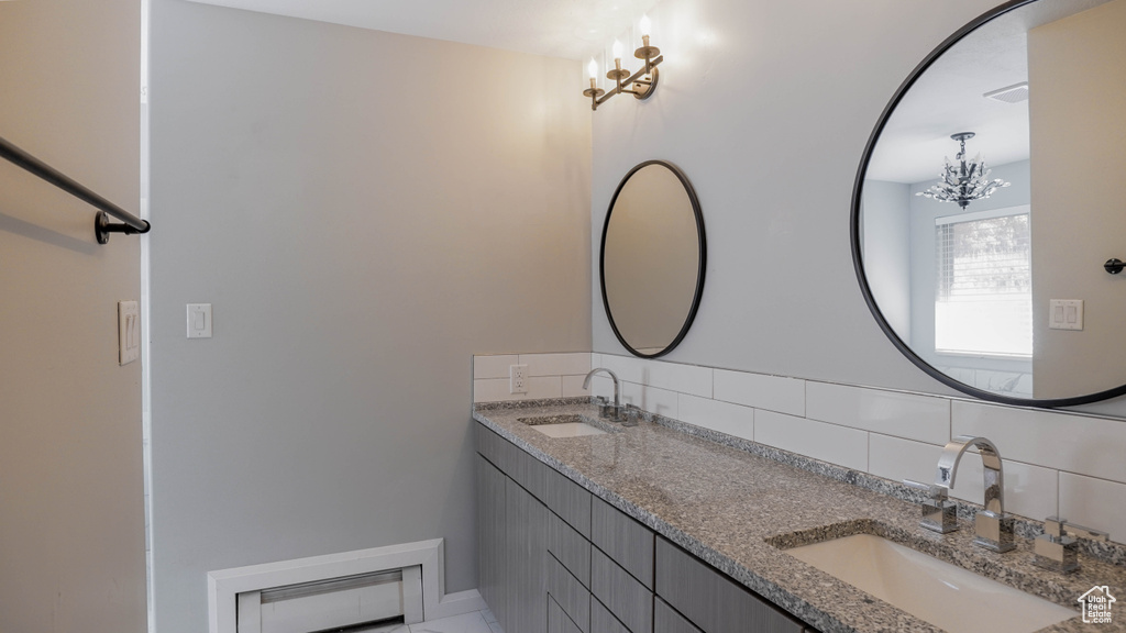 Bathroom with vanity, backsplash, and a notable chandelier