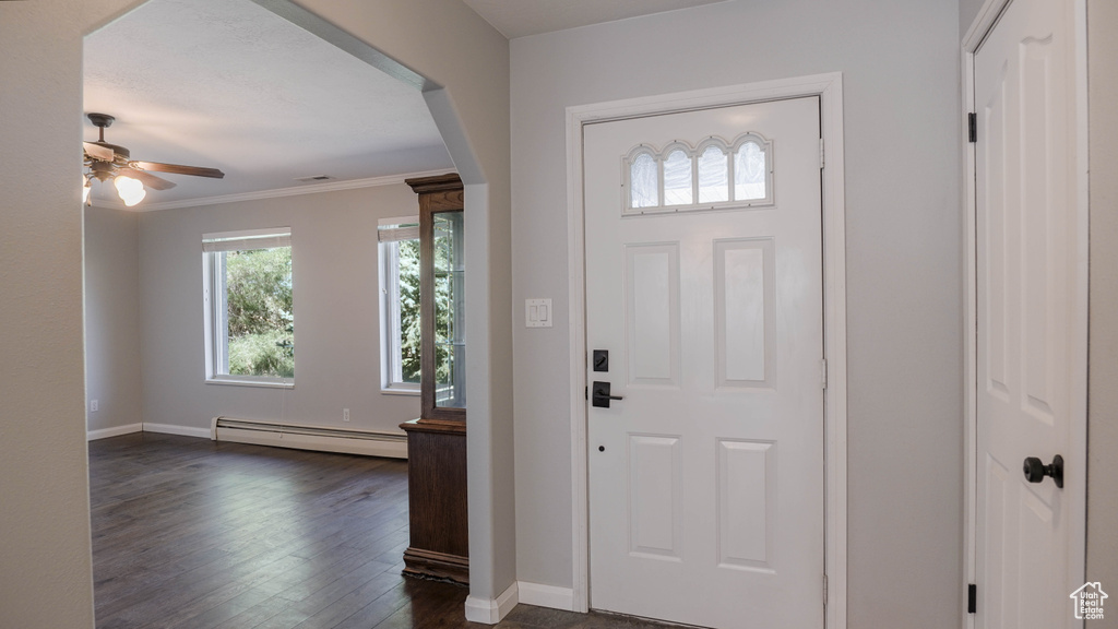 Foyer with ornamental molding, baseboard heating, ceiling fan, and dark wood-type flooring