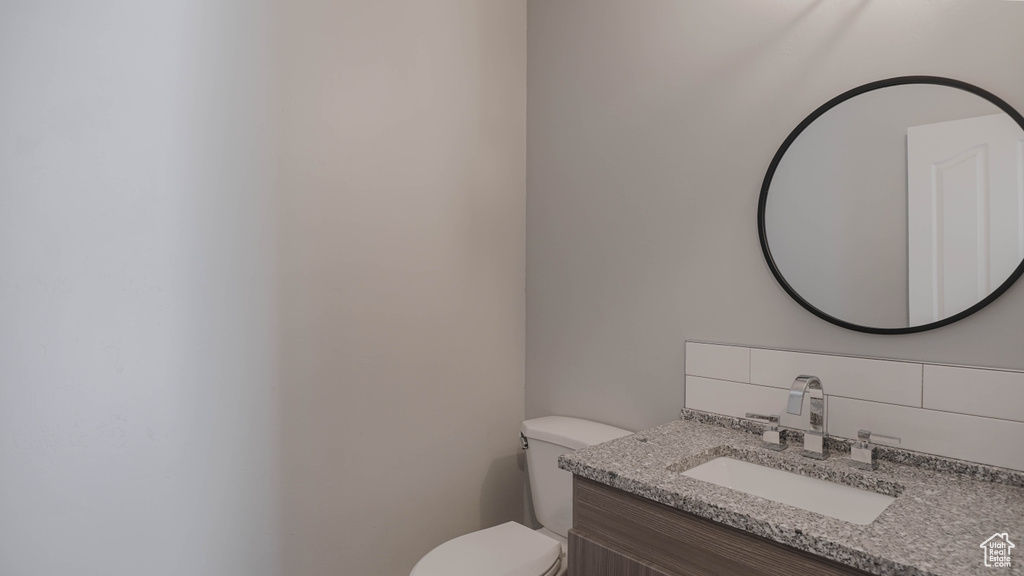 Bathroom with vanity, toilet, and tasteful backsplash