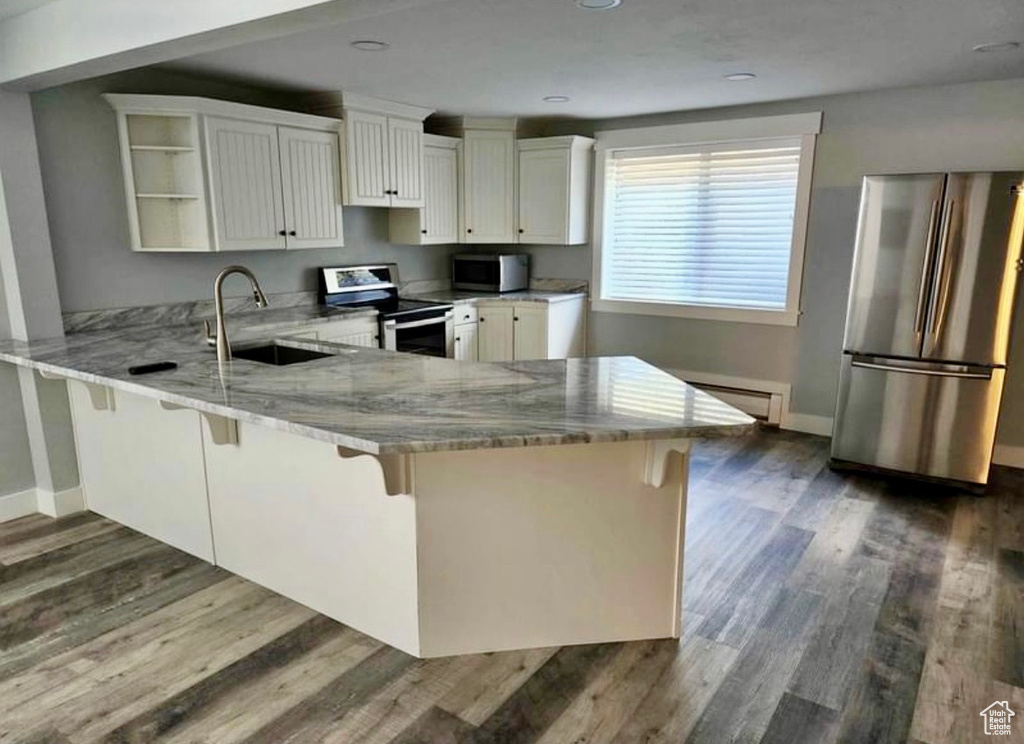 Kitchen featuring a kitchen bar, sink, stainless steel appliances, and kitchen peninsula