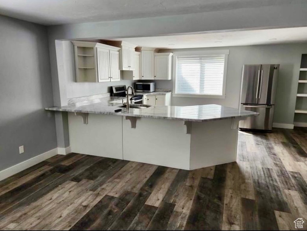 Kitchen featuring a kitchen breakfast bar, kitchen peninsula, dark hardwood / wood-style floors, and stainless steel appliances