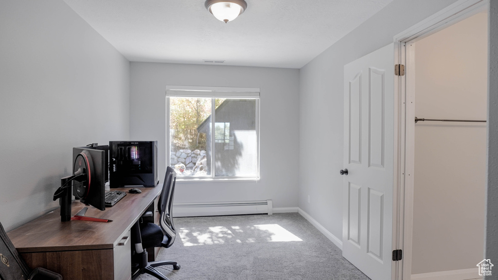 Carpeted office space with a baseboard heating unit