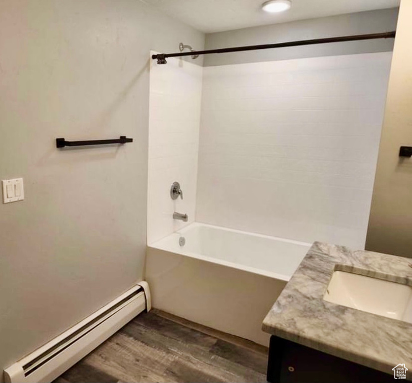 Bathroom with tub / shower combination, a baseboard heating unit, hardwood / wood-style flooring, and vanity