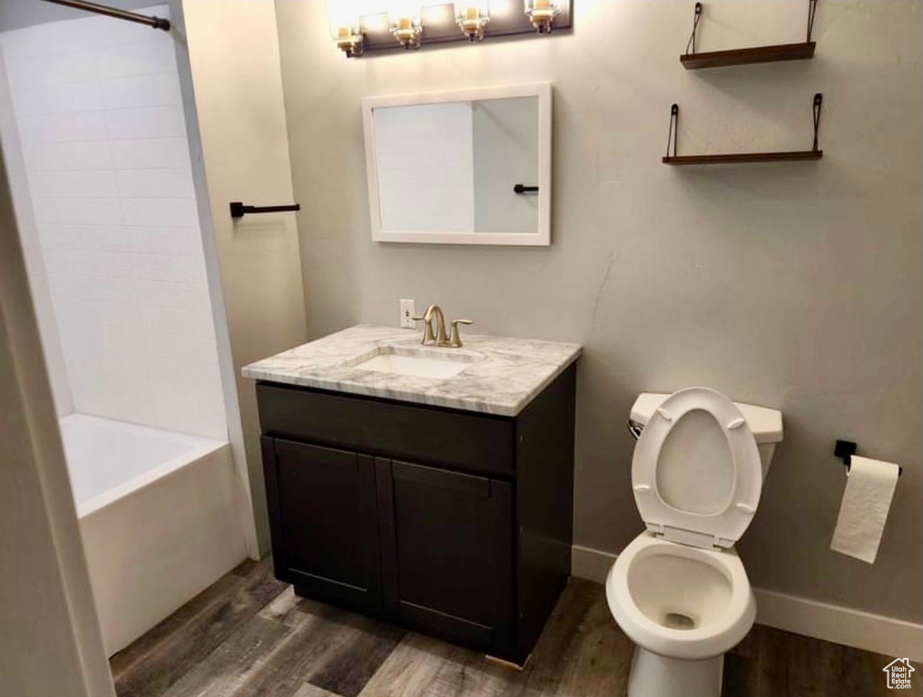 Full bathroom featuring shower / bath combination, hardwood / wood-style flooring, vanity, and toilet