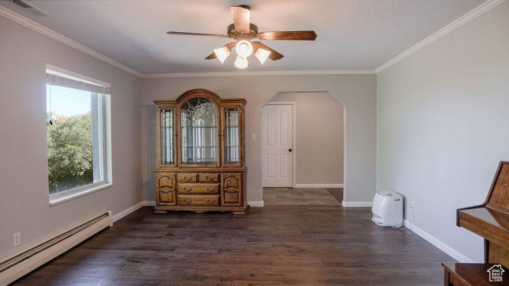 Interior space featuring crown molding, dark wood-type flooring, a baseboard heating unit, and ceiling fan