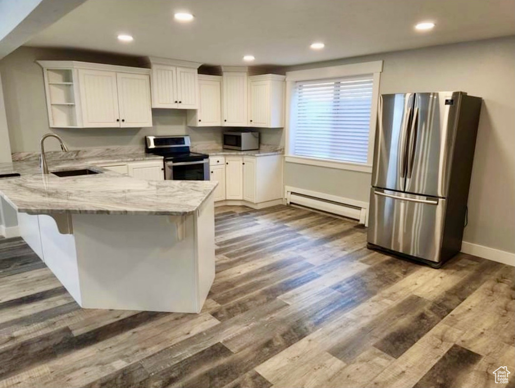 Kitchen with white cabinets, kitchen peninsula, appliances with stainless steel finishes, and sink