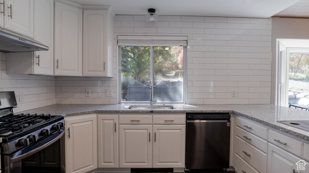 Kitchen with white cabinets, dishwasher, range with gas stovetop, and a wealth of natural light