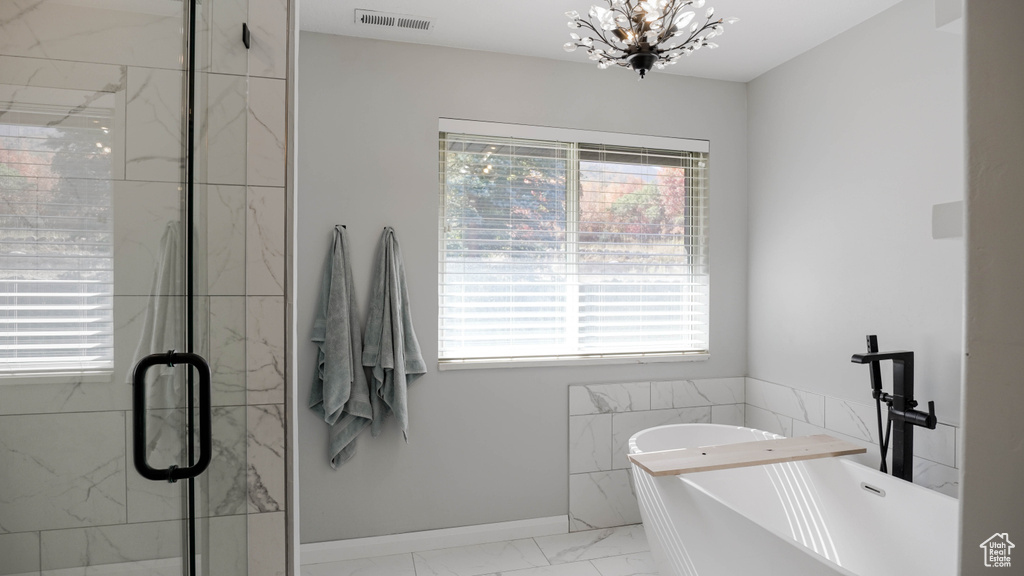 Bathroom featuring plus walk in shower and a chandelier