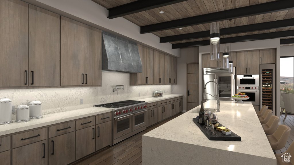 Kitchen with pendant lighting, beamed ceiling, ventilation hood, appliances with stainless steel finishes, and hardwood / wood-style floors