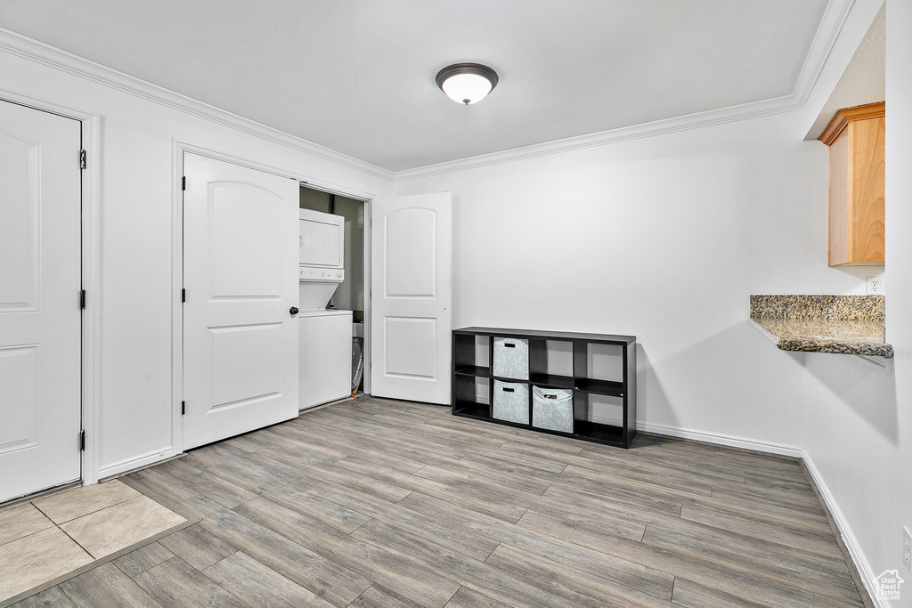 Interior space featuring light hardwood / wood-style flooring, stacked washer / dryer, and crown molding