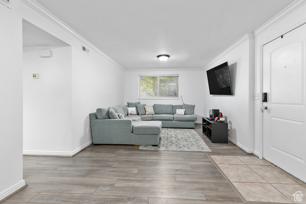 Living room featuring ornamental molding and light hardwood / wood-style flooring