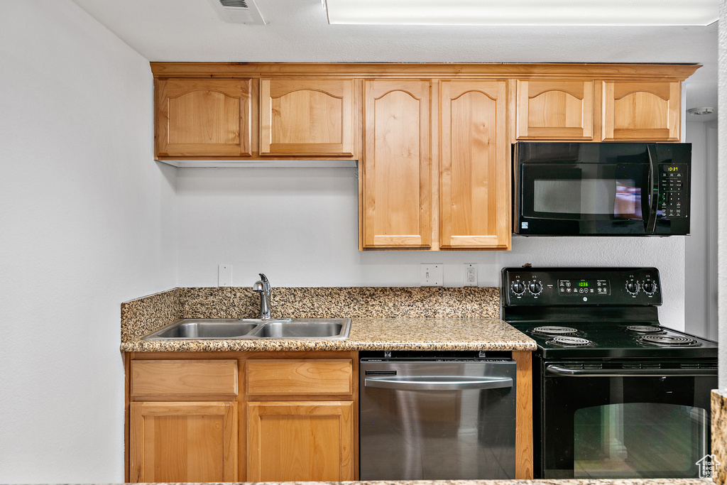 Kitchen featuring light brown cabinetry, sink, and black appliances