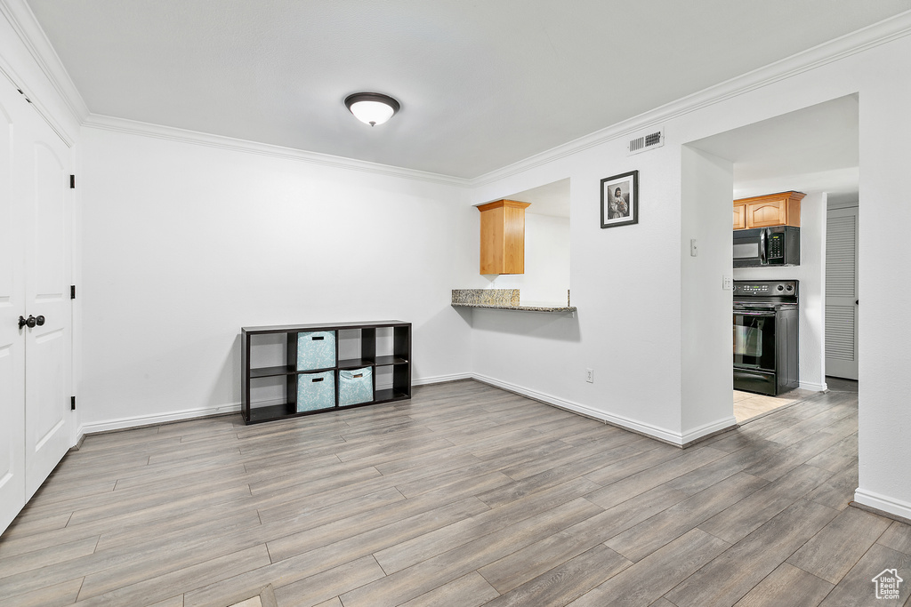Spare room with light wood-type flooring and ornamental molding