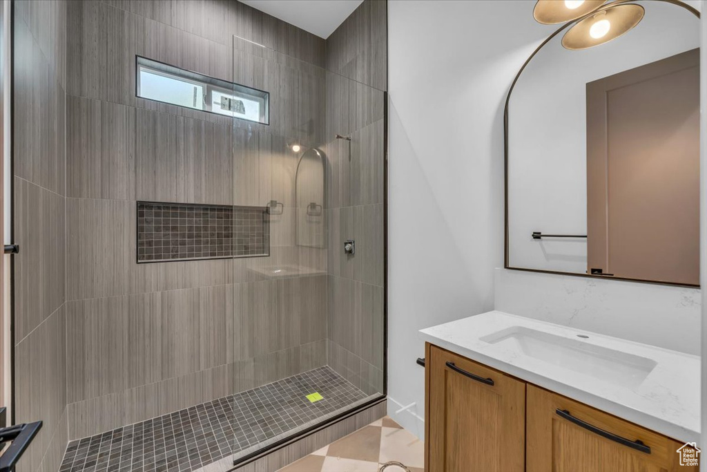 Bathroom featuring a tile shower, vanity, and tile patterned floors