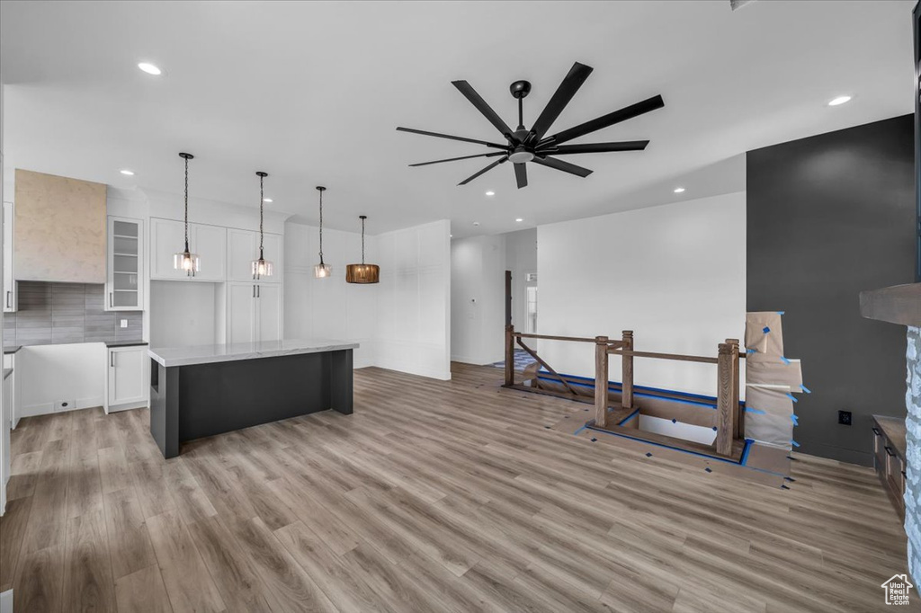 Kitchen featuring light hardwood / wood-style floors, white cabinetry, pendant lighting, a center island, and ceiling fan