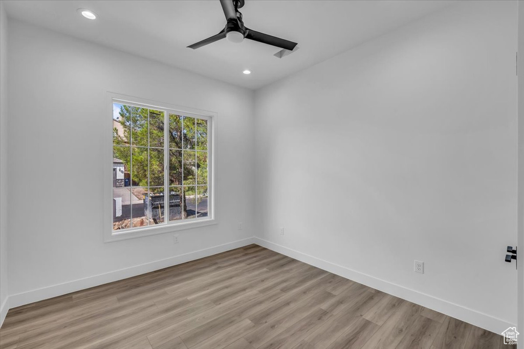 Empty room with ceiling fan and light hardwood / wood-style flooring