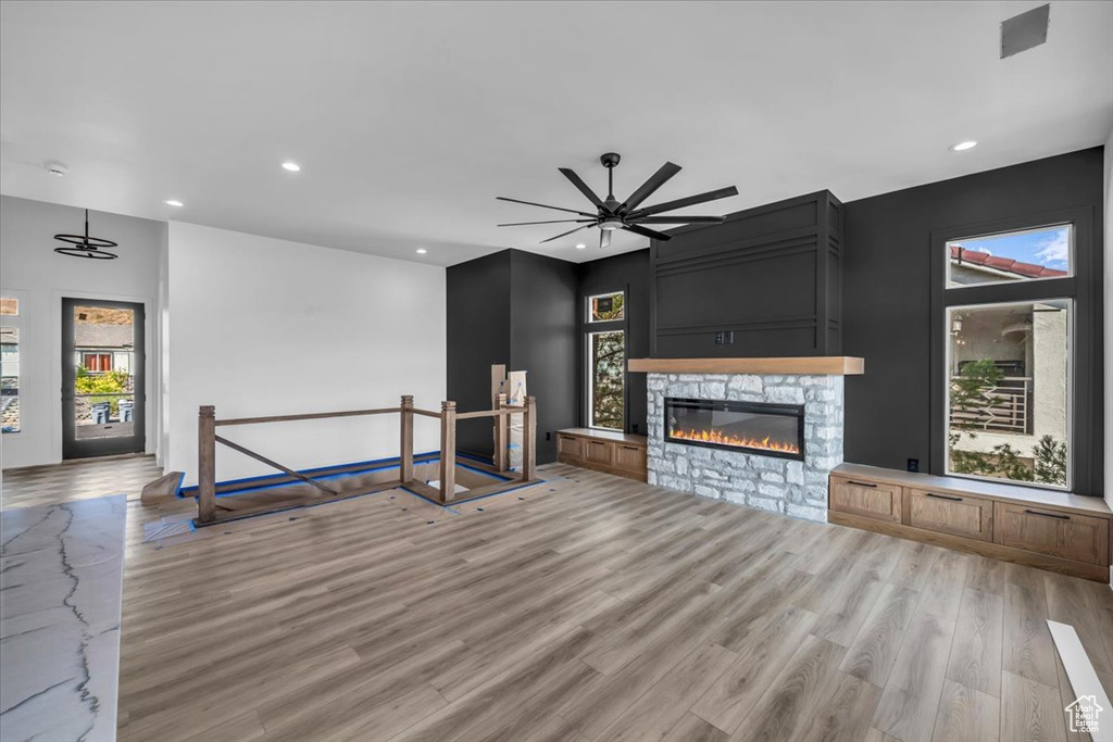 Living room featuring a stone fireplace, ceiling fan, and light hardwood / wood-style flooring