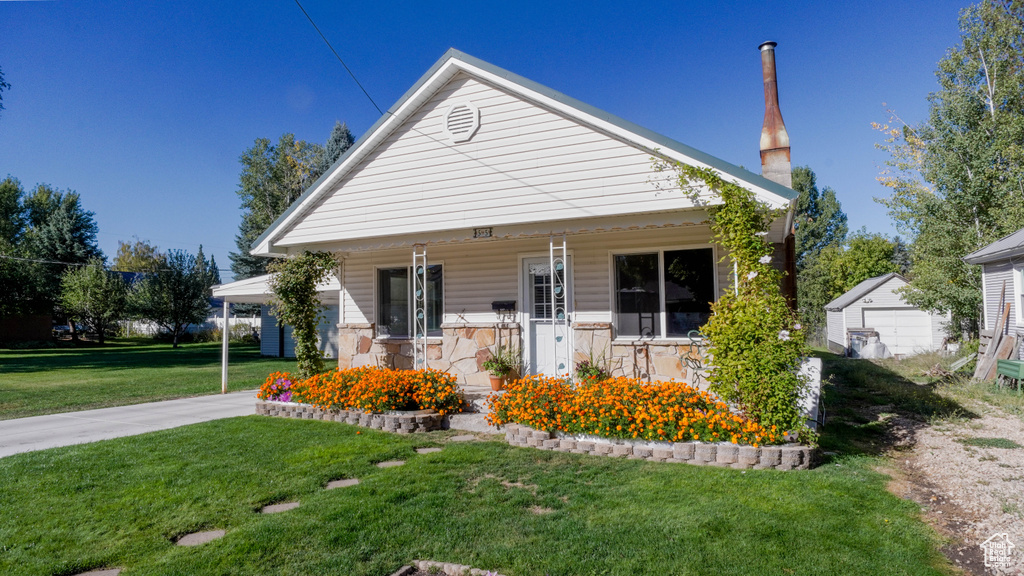 Bungalow-style home featuring a front yard, an outdoor structure, a porch, and a garage