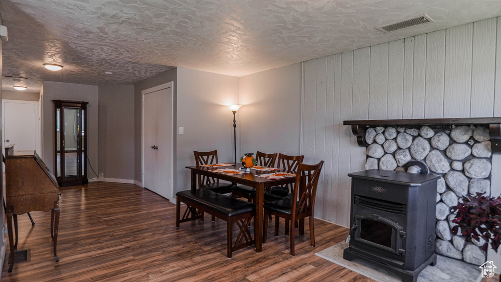 Dining space featuring a wood stove, a textured ceiling, and dark hardwood / wood-style floors