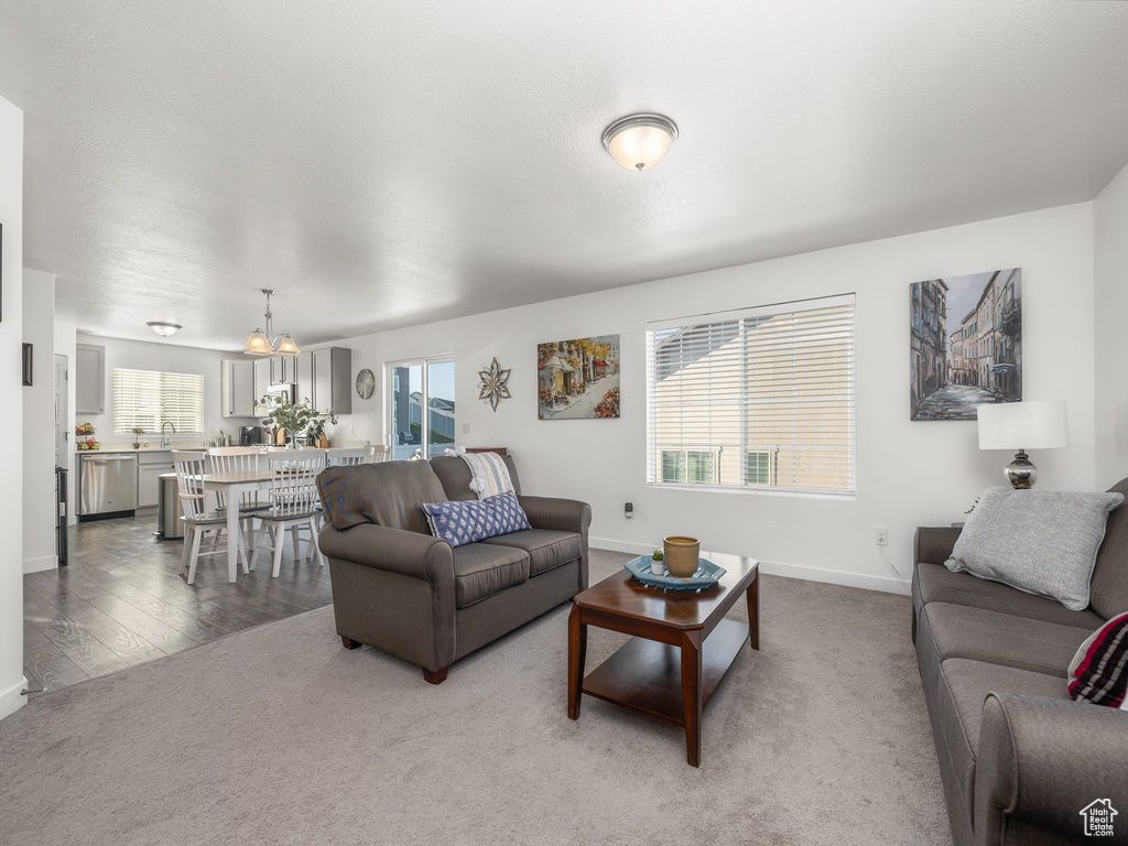 Carpeted living room featuring a healthy amount of sunlight, sink, and a notable chandelier