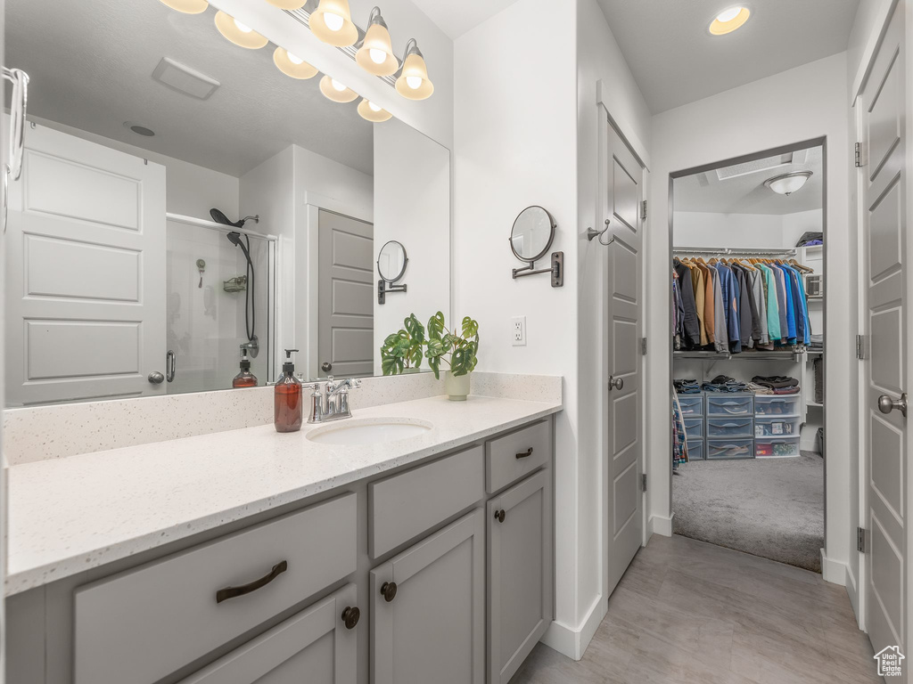 Bathroom featuring a shower with shower door and vanity