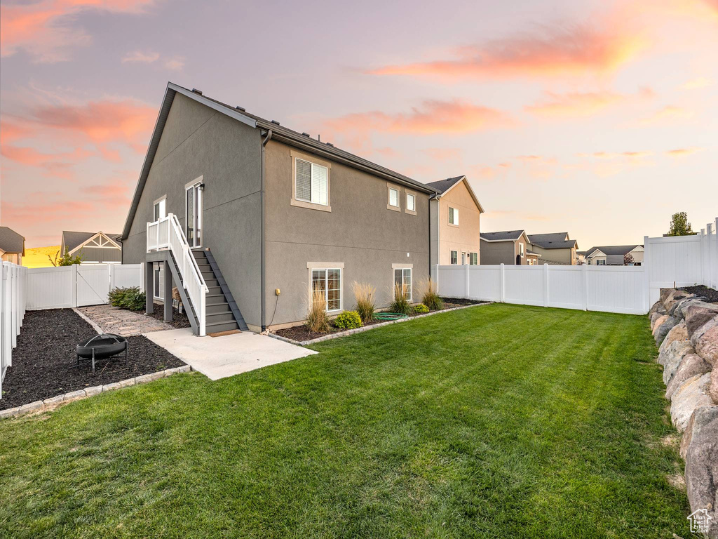 Back house at dusk featuring a yard