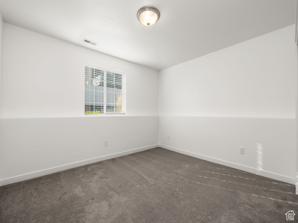 Empty room featuring vaulted ceiling and dark carpet