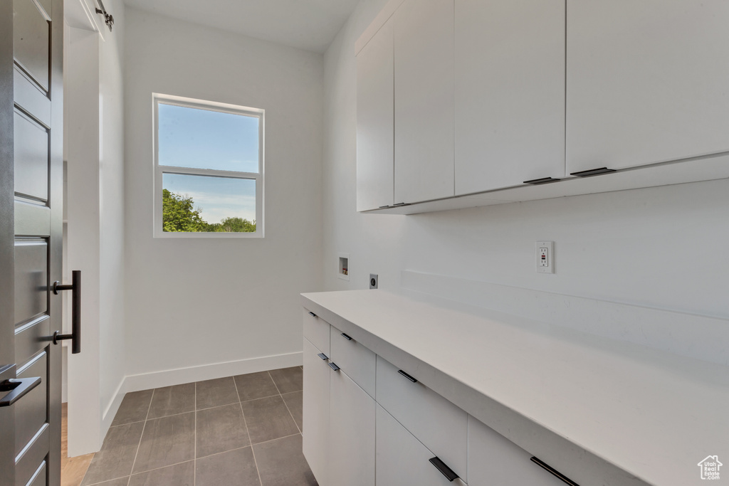 Clothes washing area with cabinets, hookup for an electric dryer, washer hookup, and light tile patterned floors