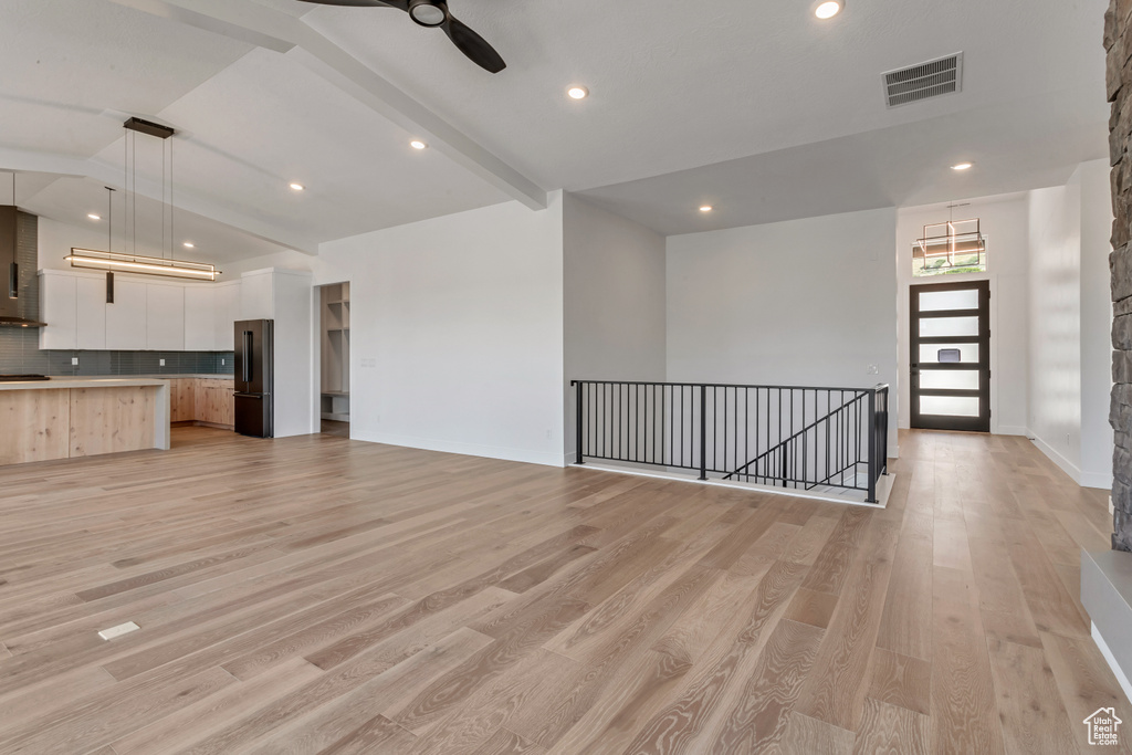 Unfurnished living room featuring ceiling fan, vaulted ceiling with beams, and light hardwood / wood-style floors